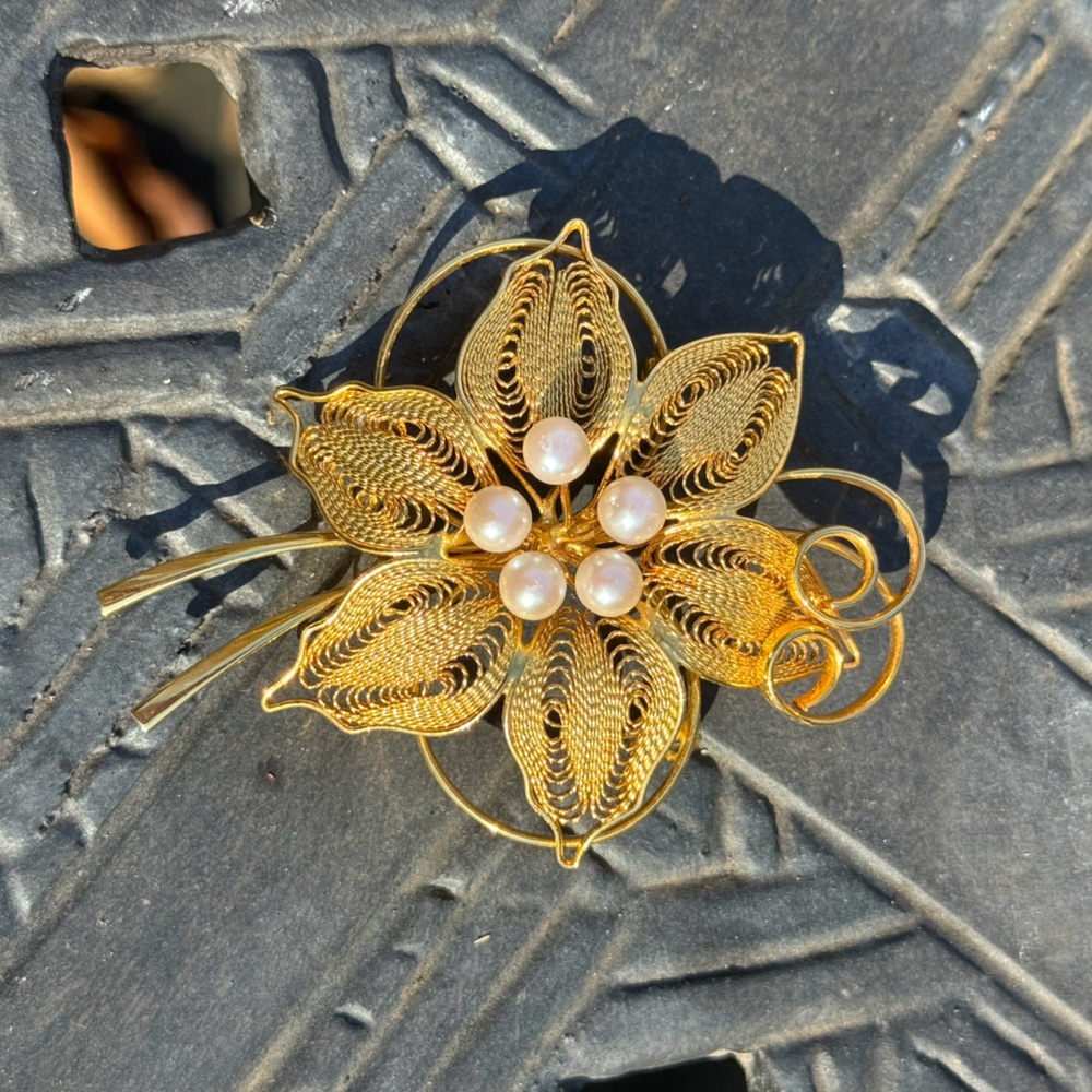 Oversized golden flower brooch with stylized, “pearl” stamen.
